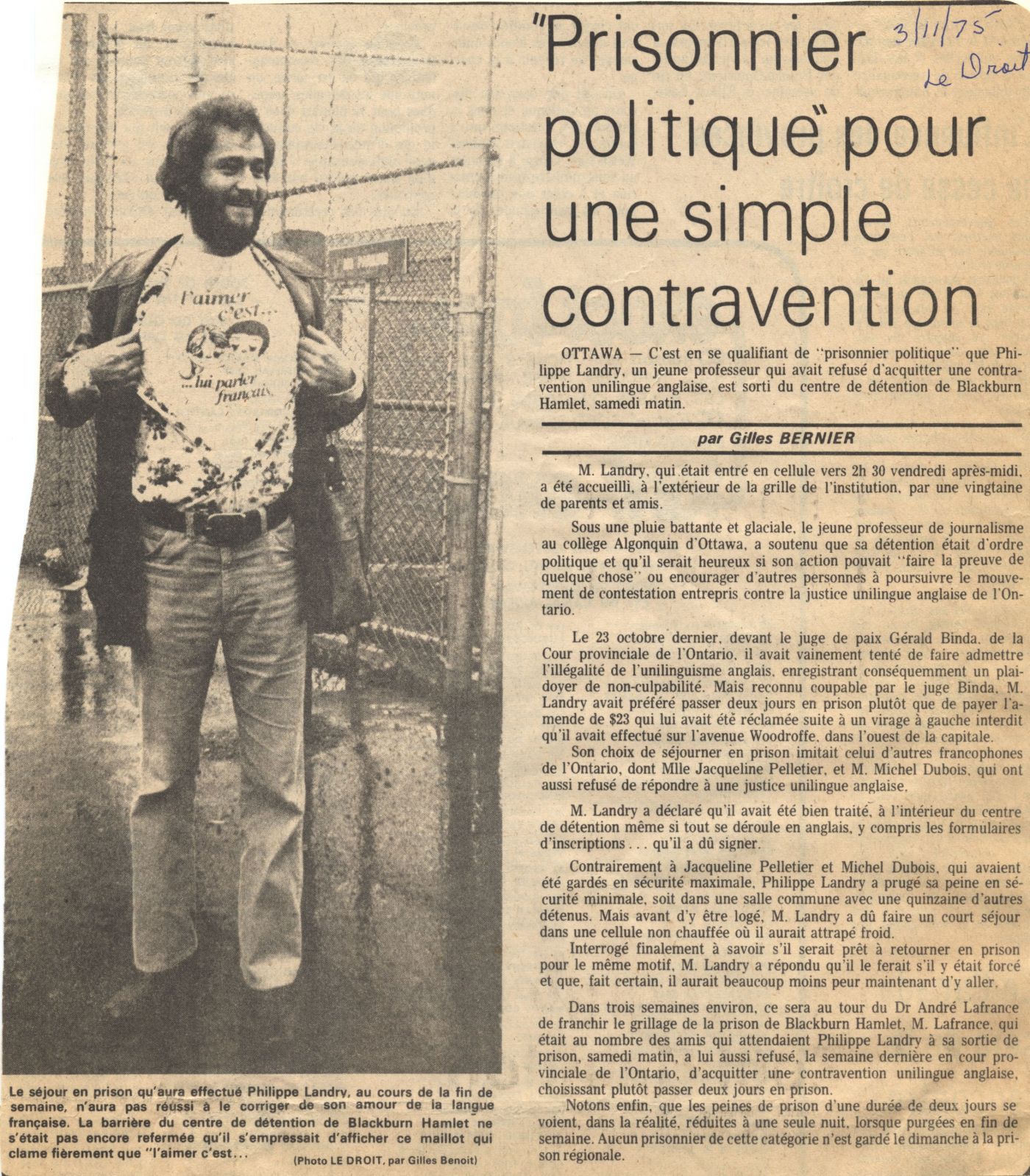 Newspaper article written in French, with the source and date handwritten in blue ink. The article is accompanied by a black and white photograph of a young bearded man revealing a T-shirt with the words “L’aimer c’est… lui parler français” (Love is ... speaking to them in French). In the background, a chain link fence.